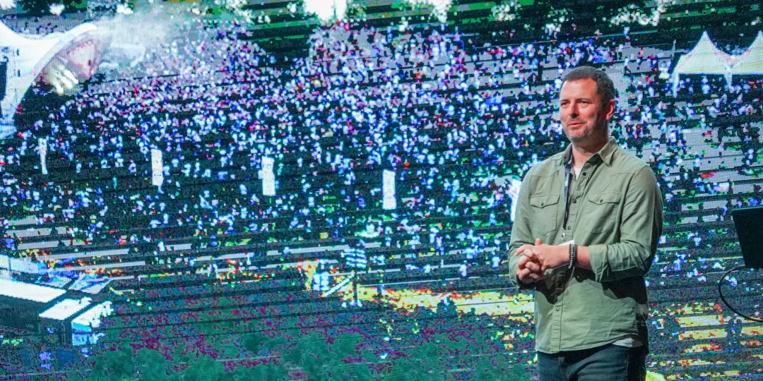 En man står framför en stor skärm.